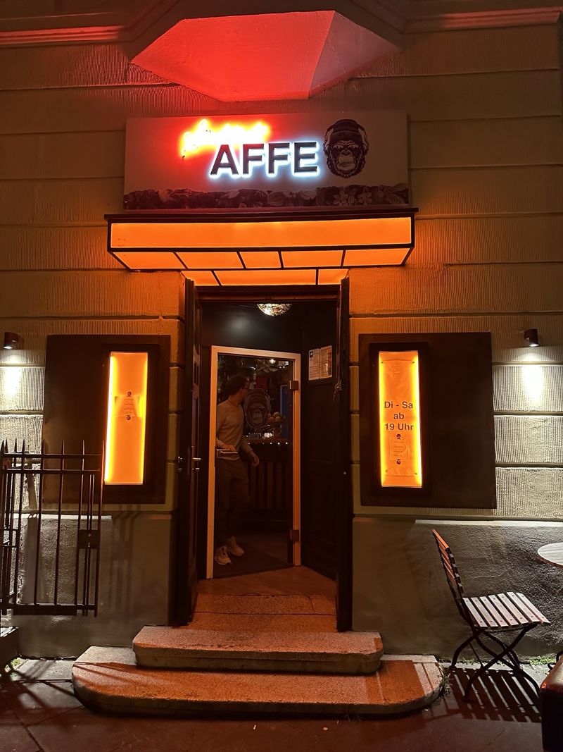 Eingang der Bar bei Nacht mit leuchtendem AFFE-Schild und orangefarbenem Vordach