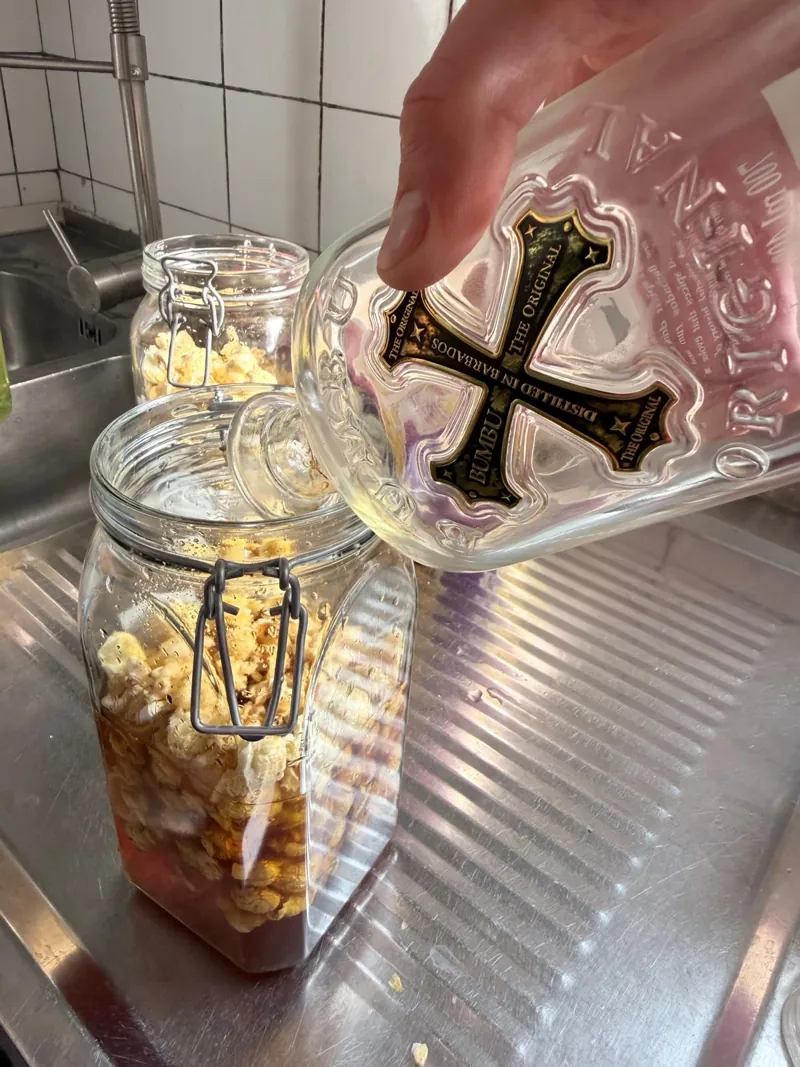Rum wird in ein Glas mit Popcorn gegossen